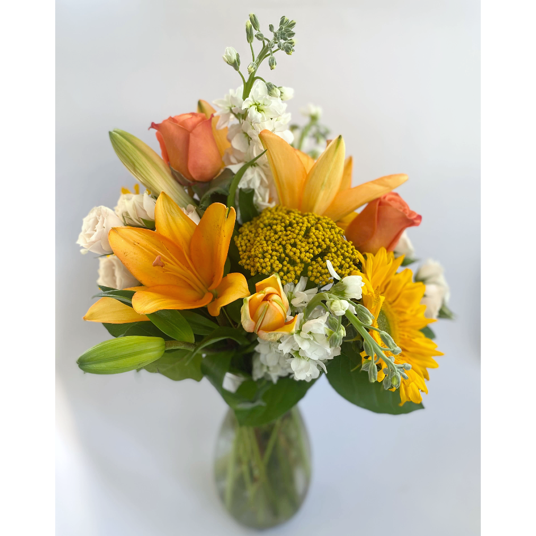Close-up of a colorful floral arrangement, featuring yellow, pink, and white blossoms in a glass vase.