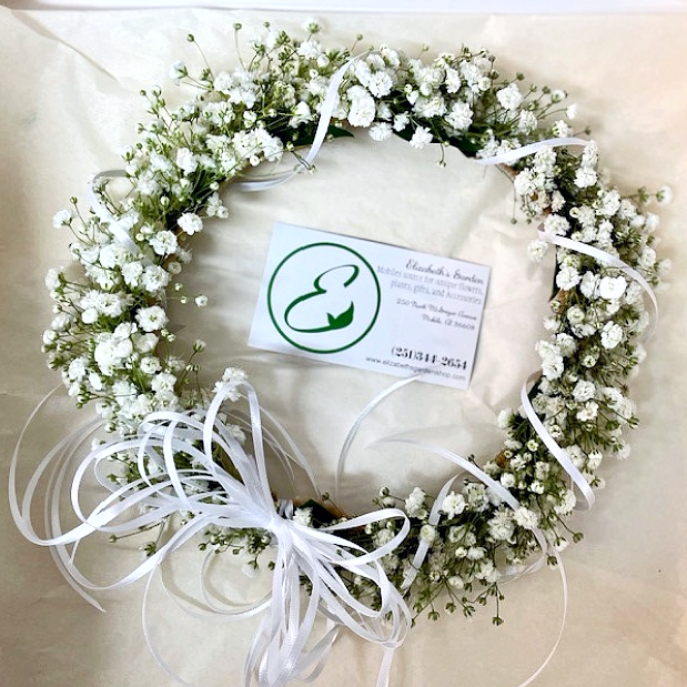 White baby's breath flower wreath with white ribbons, business card in center.
