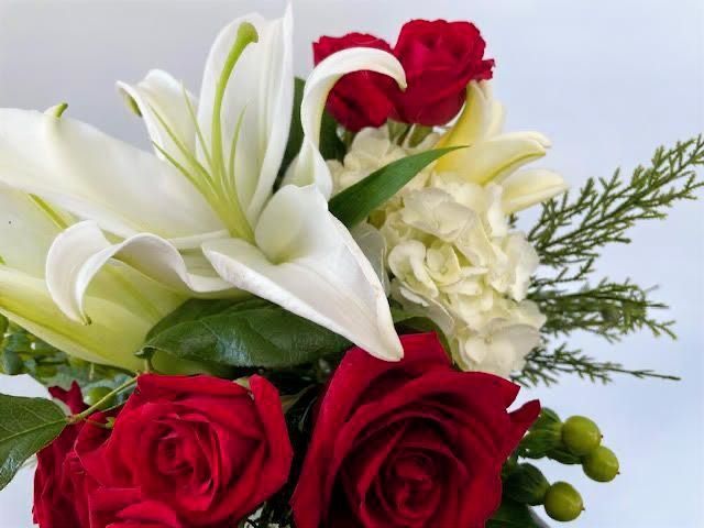 Close-up of a bouquet with yellow, pink, and white flowers, including roses and small pink blossoms.