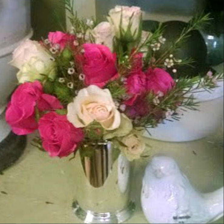 A vase filled with pink and white roses in a silver julep cup.