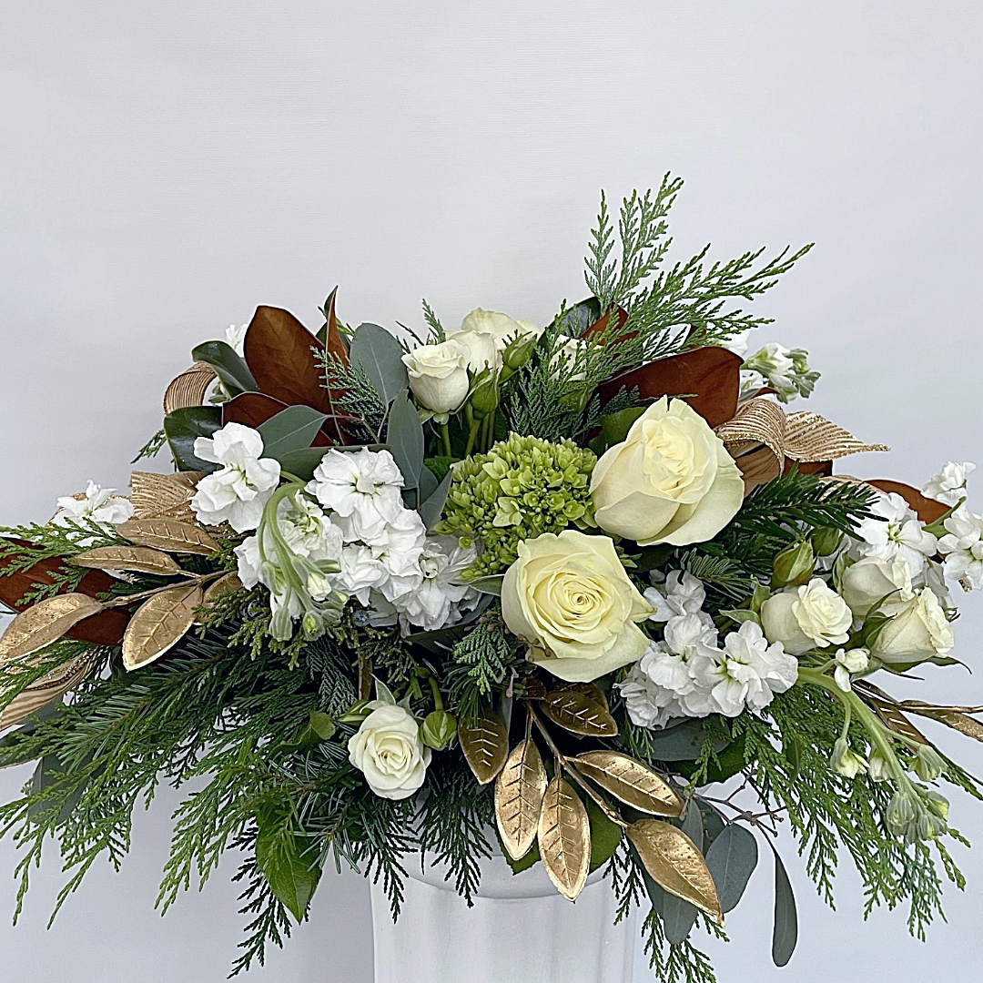 White and gold floral arrangement with roses and greenery.