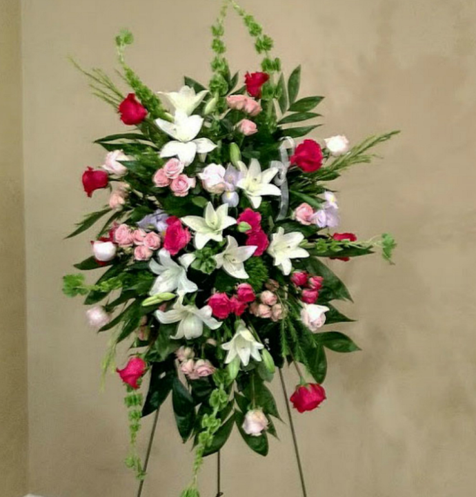 Floral standing spray with white lilies, red roses, and pink accents.