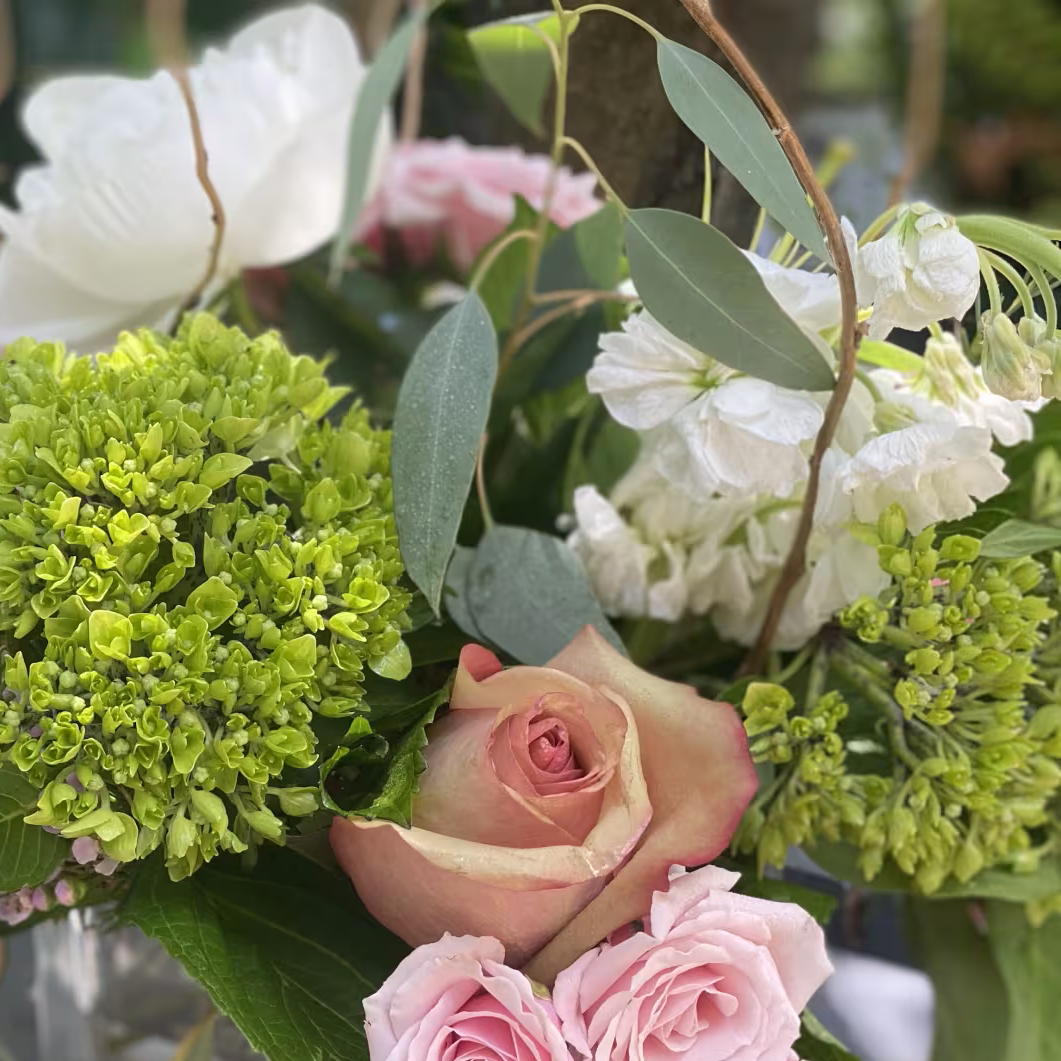 Close-up of a floral arrangement with pink roses, white flowers, and green accents.