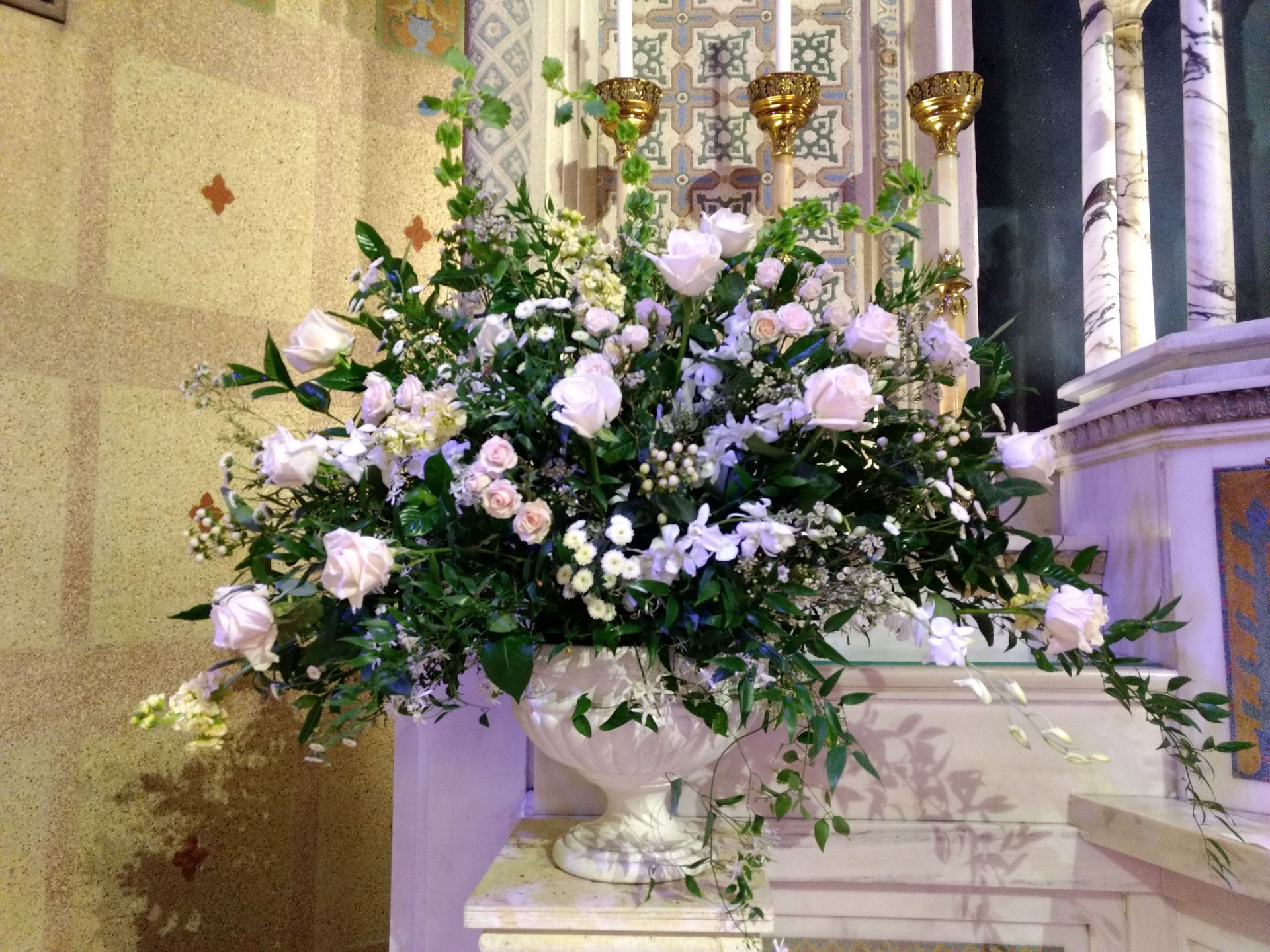 Floral arrangement of white roses and greenery in a church setting.