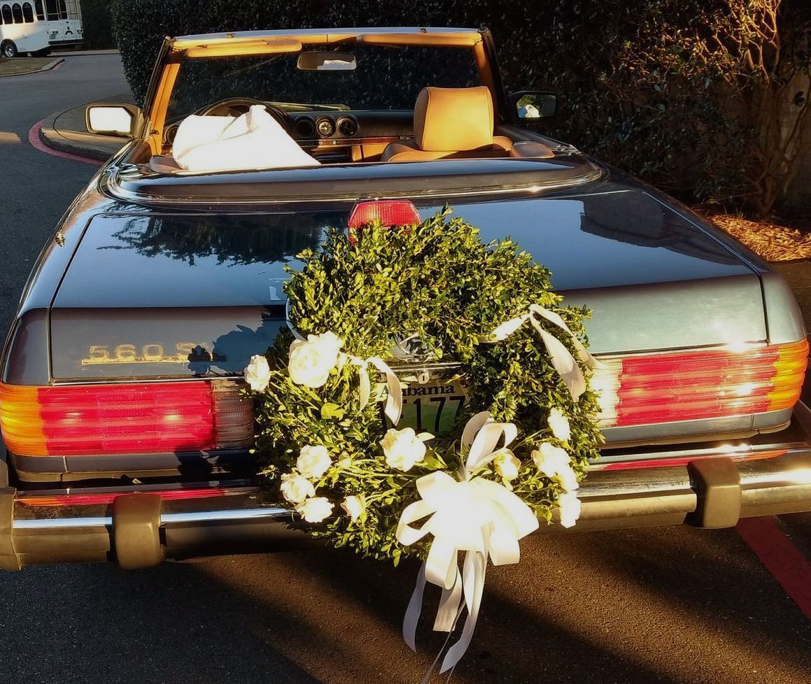Blue convertible car with a wreath on the back, likely for a wedding or celebration.
