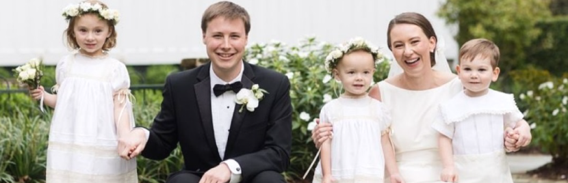 A bride and groom are posing for a picture with their flower girl.