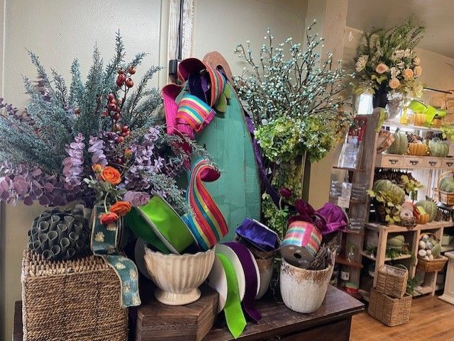 Various ribbons, flowers, and plants of different colors are arranged on a table.