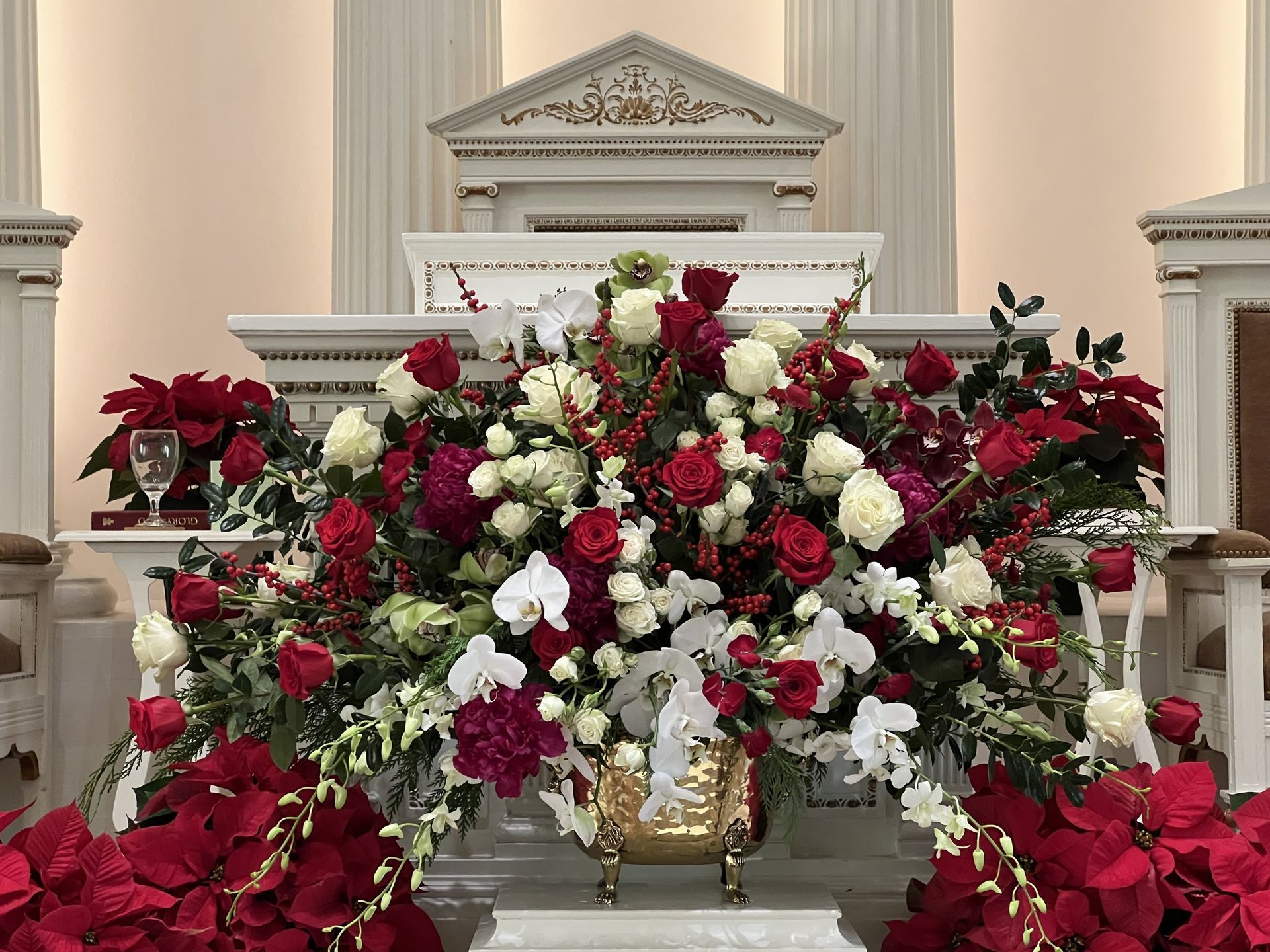 Floral arrangement of red and white flowers in front of a church altar.