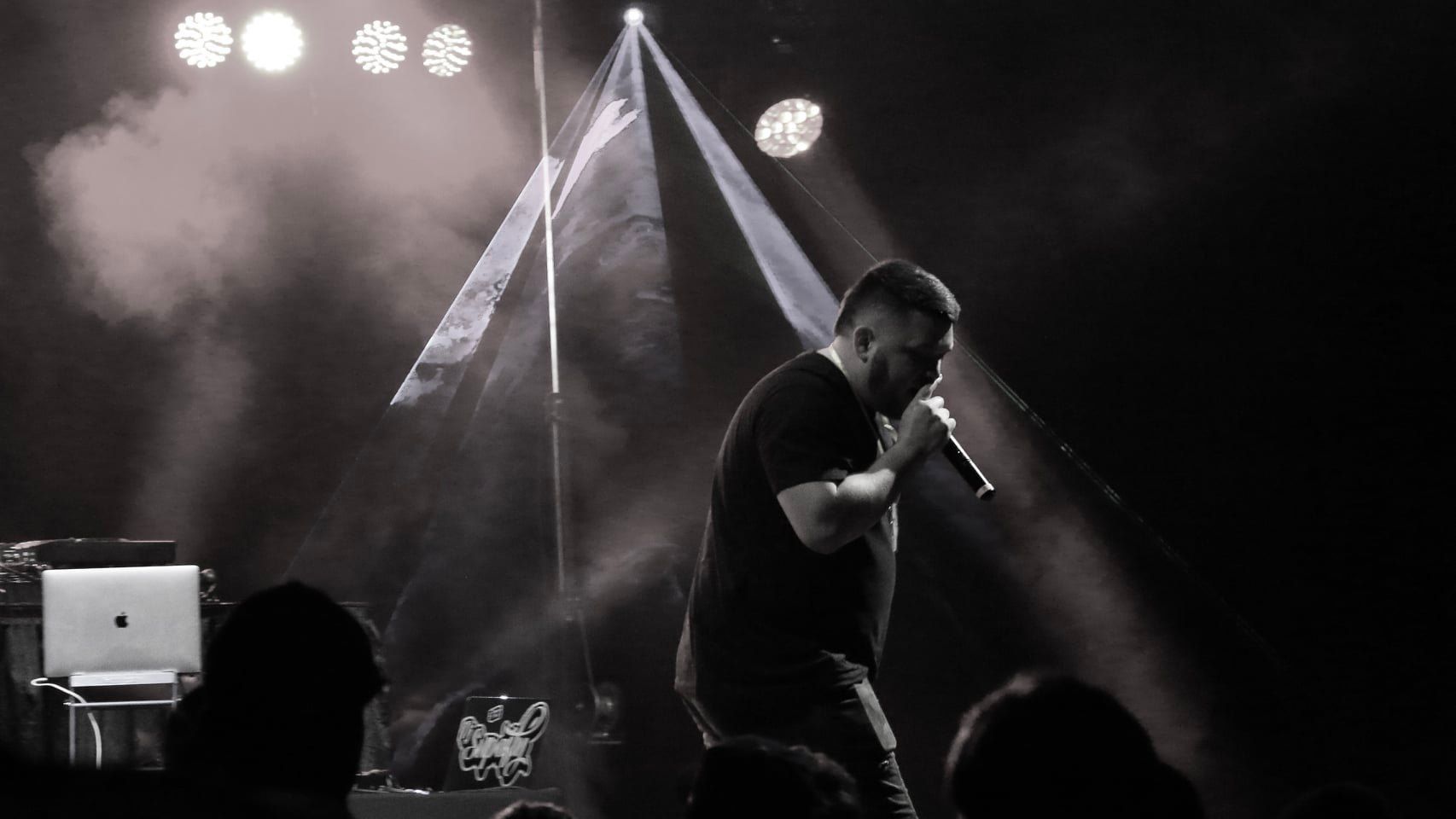 A man is singing into a microphone on a stage in front of a crowd.