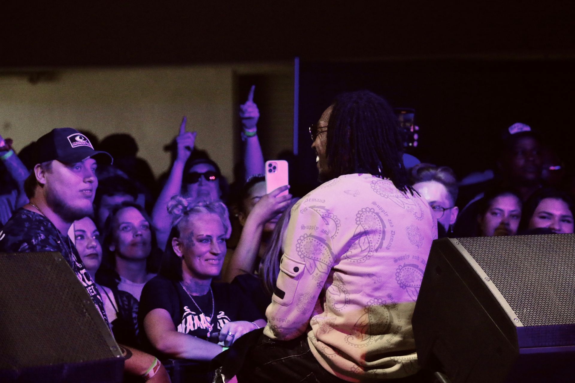 A man is sitting on a stage talking to a crowd of people.