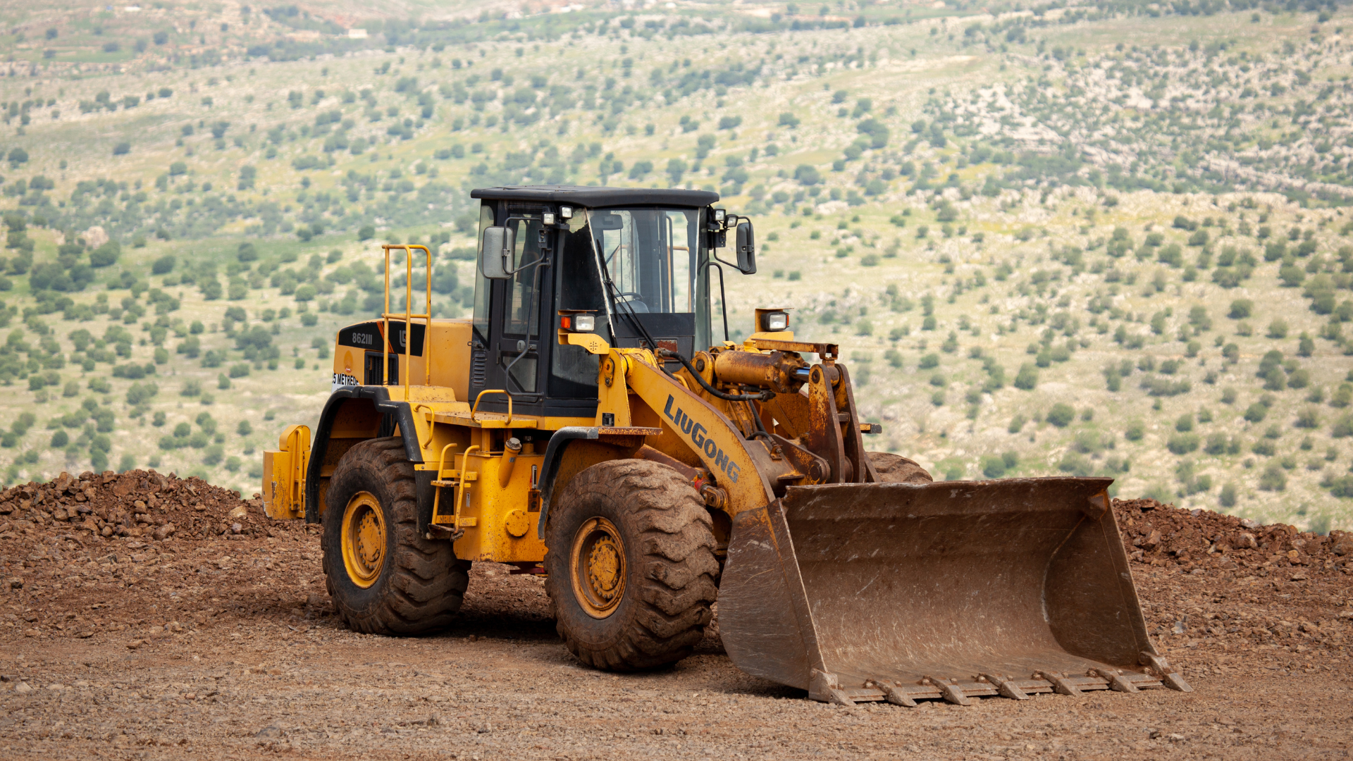 A yellow bulldozer with a large orange bucket is parked on the side of the road.