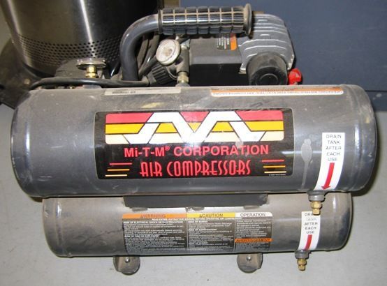 A mi-t-m corporation air compressor is sitting on the floor