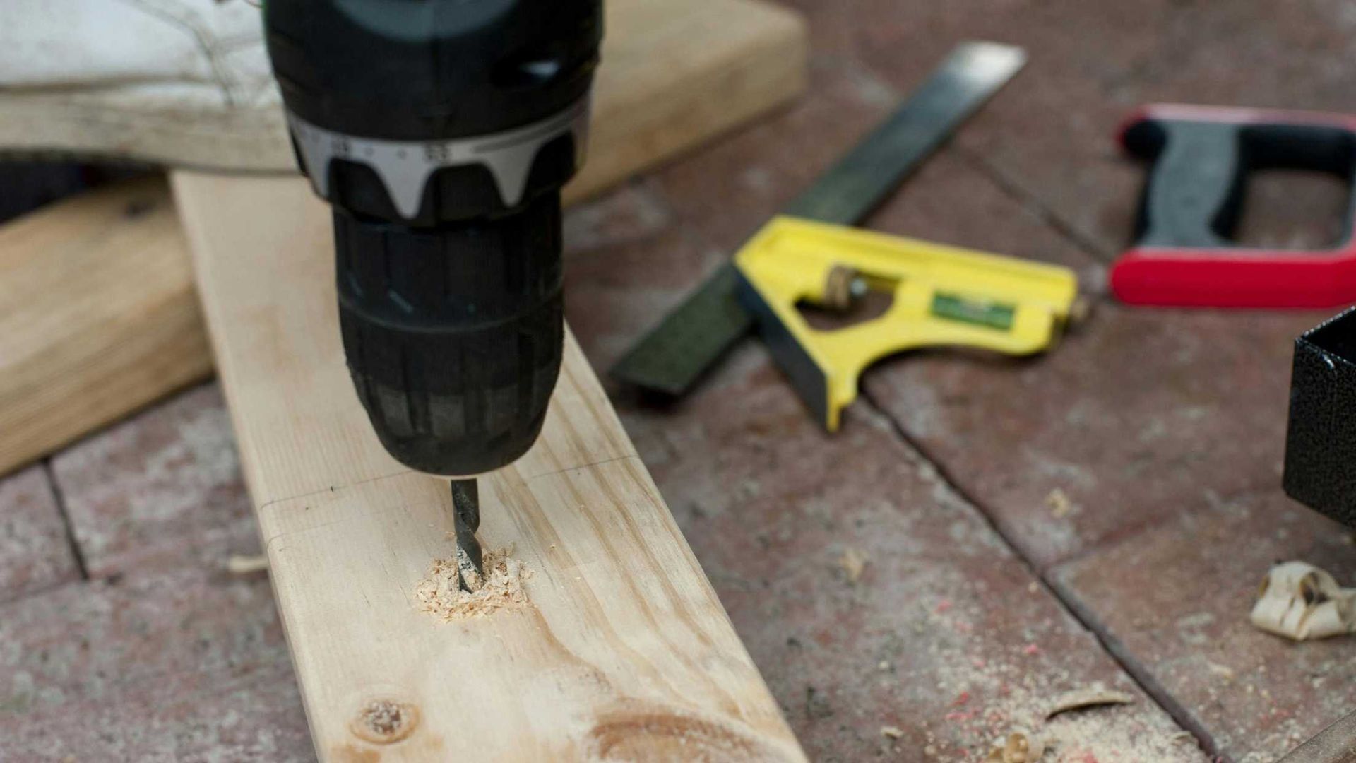 A person is using a drill to drill a hole in a piece of wood.