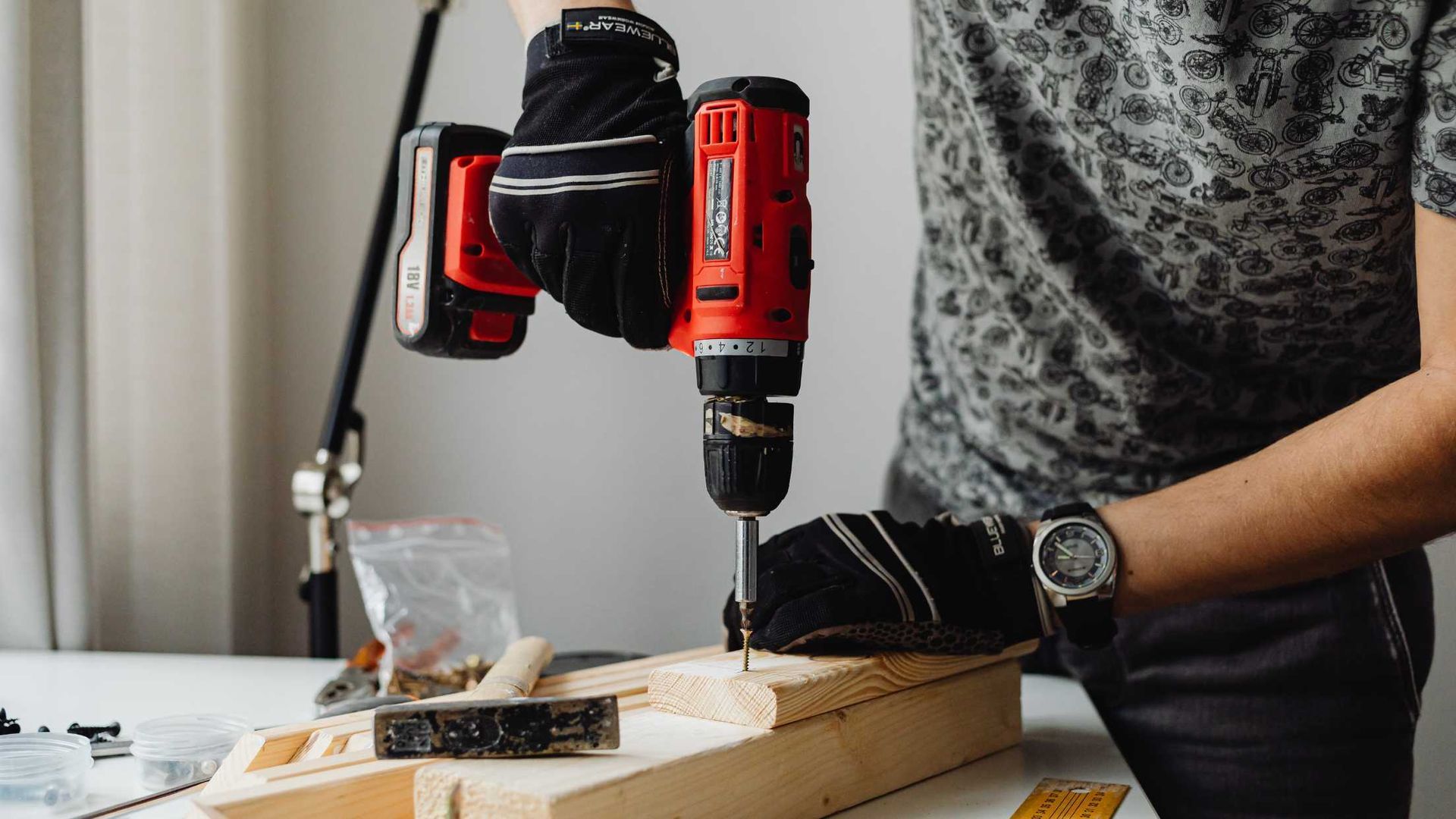 A man is using a drill to drill a hole in a piece of wood.