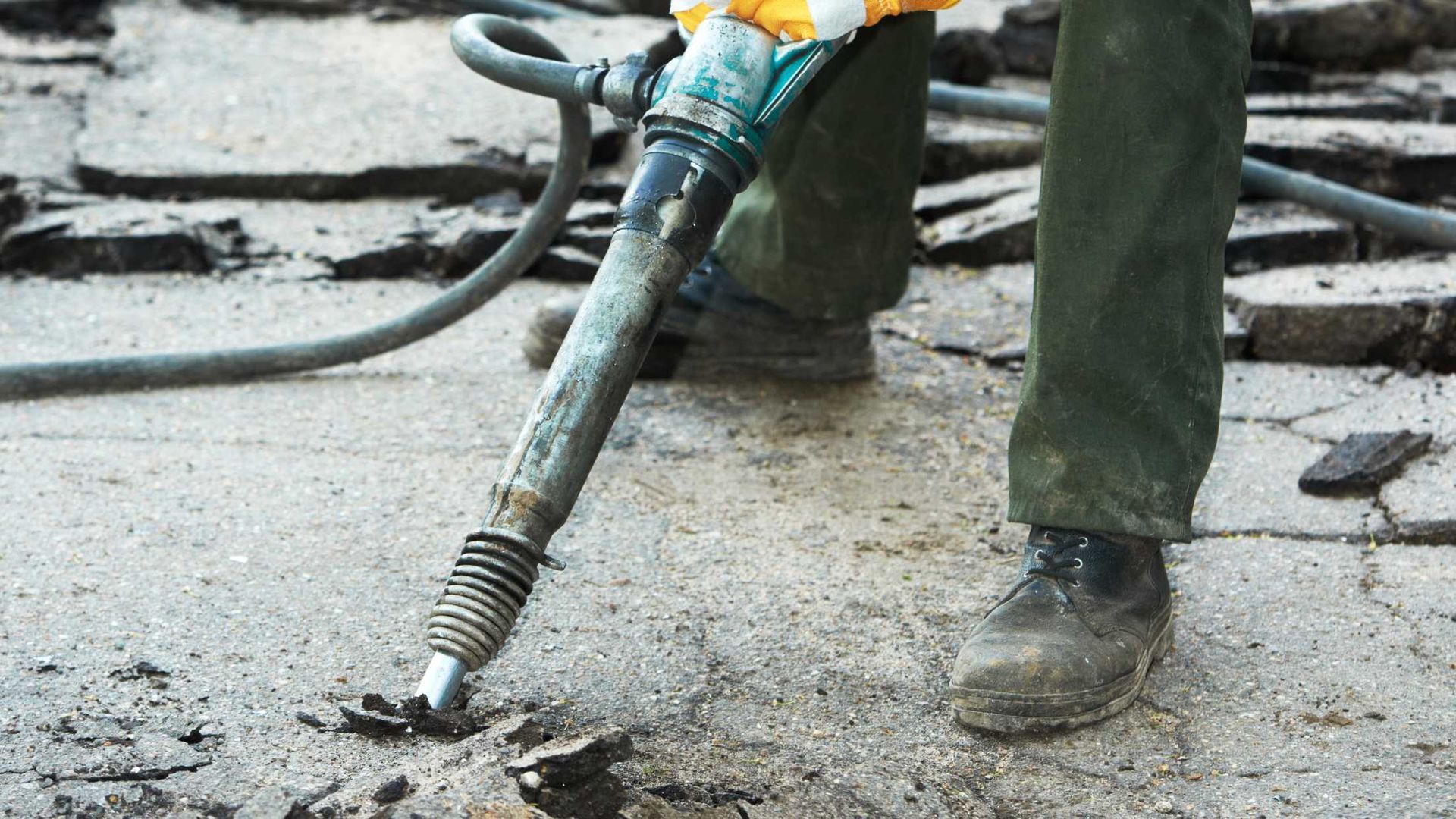 A person is using a hammer to break up concrete.