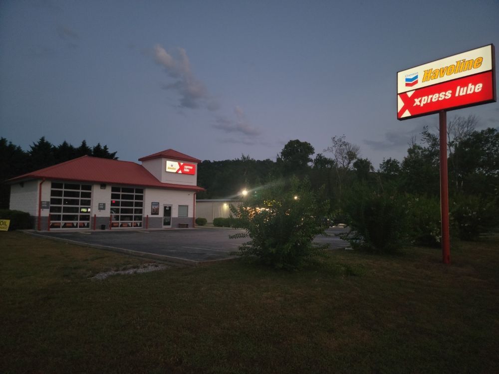 Chevron Xpress Lube at dusk. Building with red roof, sign. Dark blue sky.