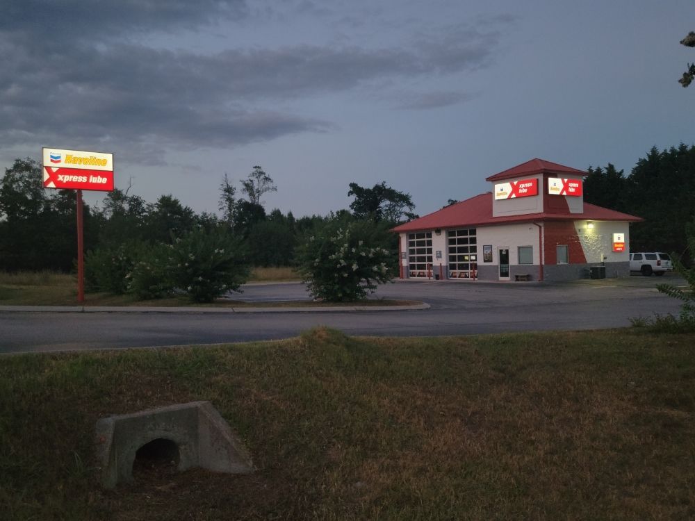 A red and white tire shop under a cloudy sky, with a road and grass in the foreground.