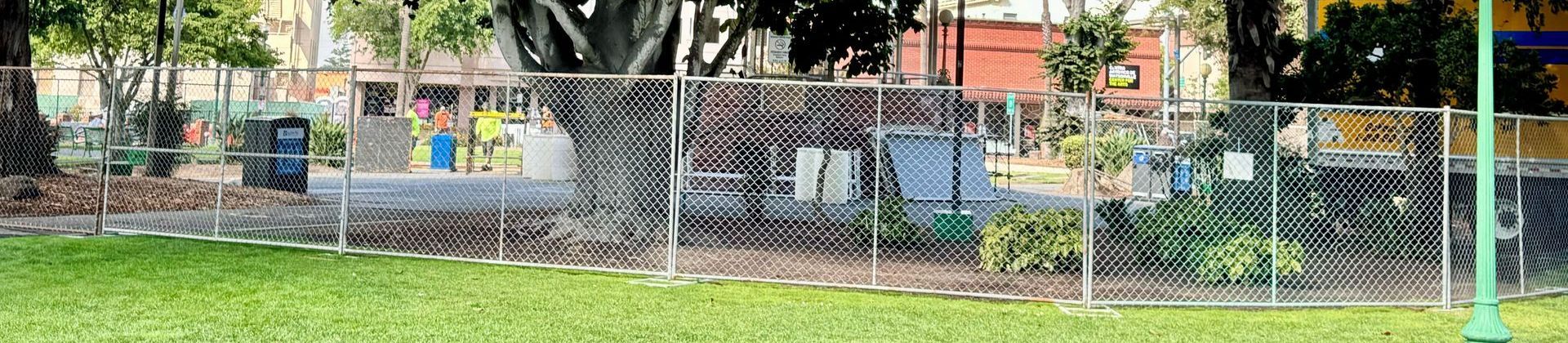 A chain link fence with a baseball field in the background