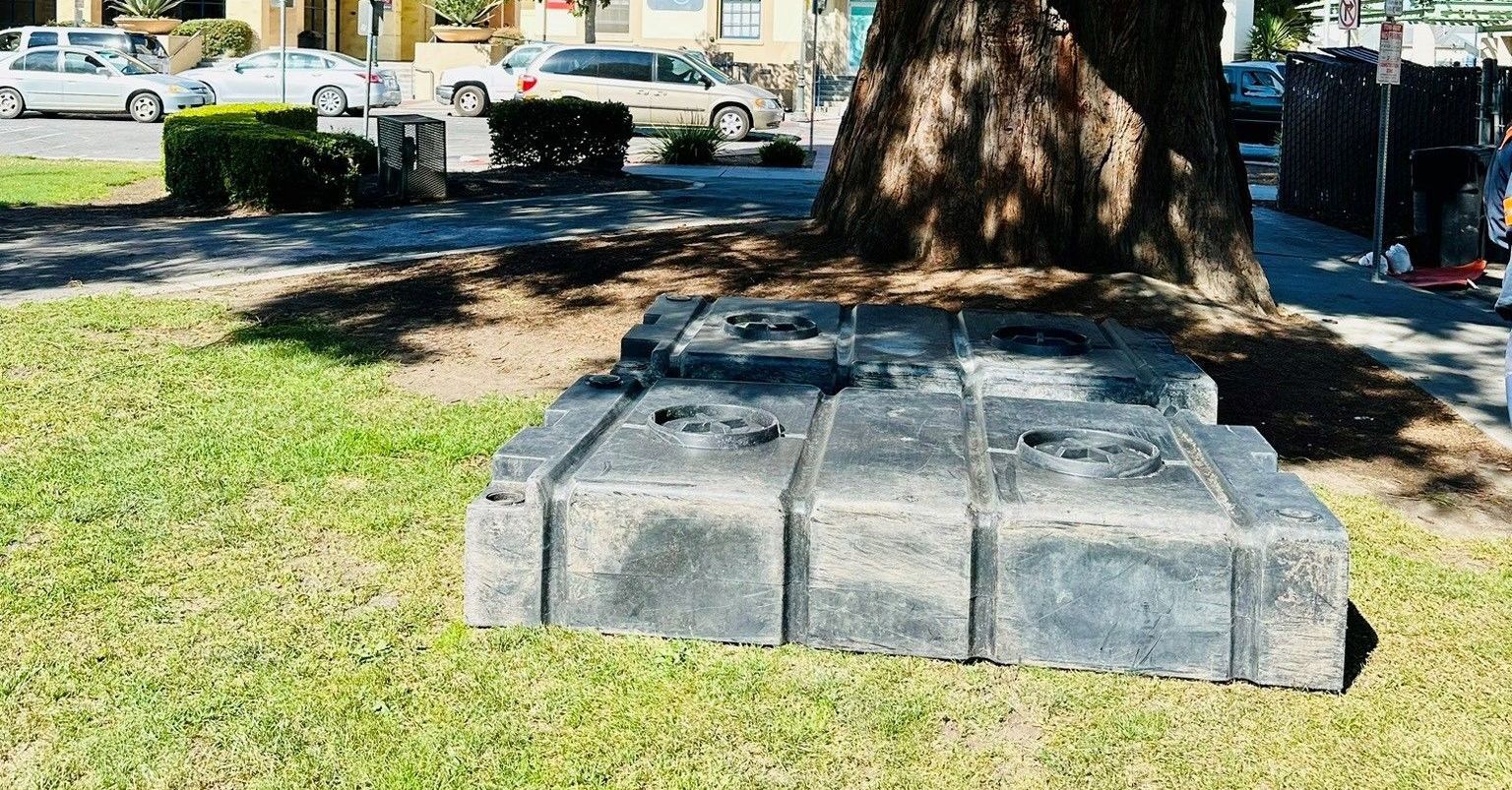 A septic tank truck is driving down a street in front of a house.