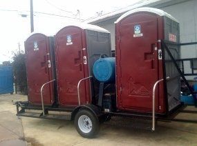 A trailer with three portable toilets attached to it.