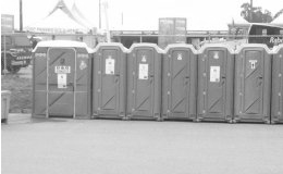 A black and white photo of a row of portable toilets