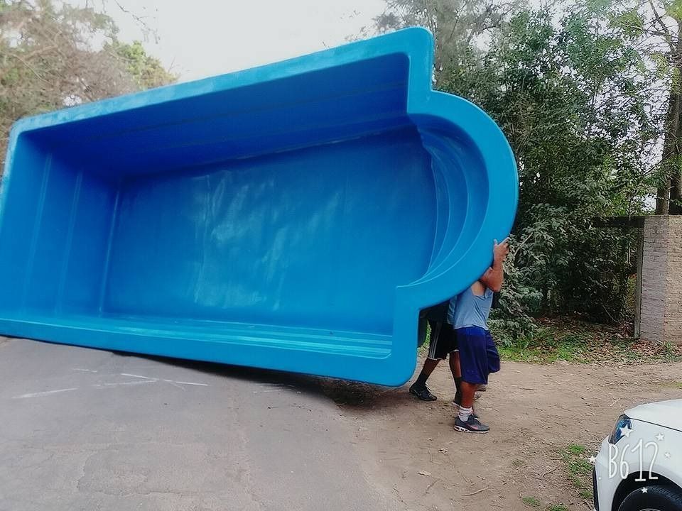 Dos personas llevan una gran concha de piscina rectangular de color azul