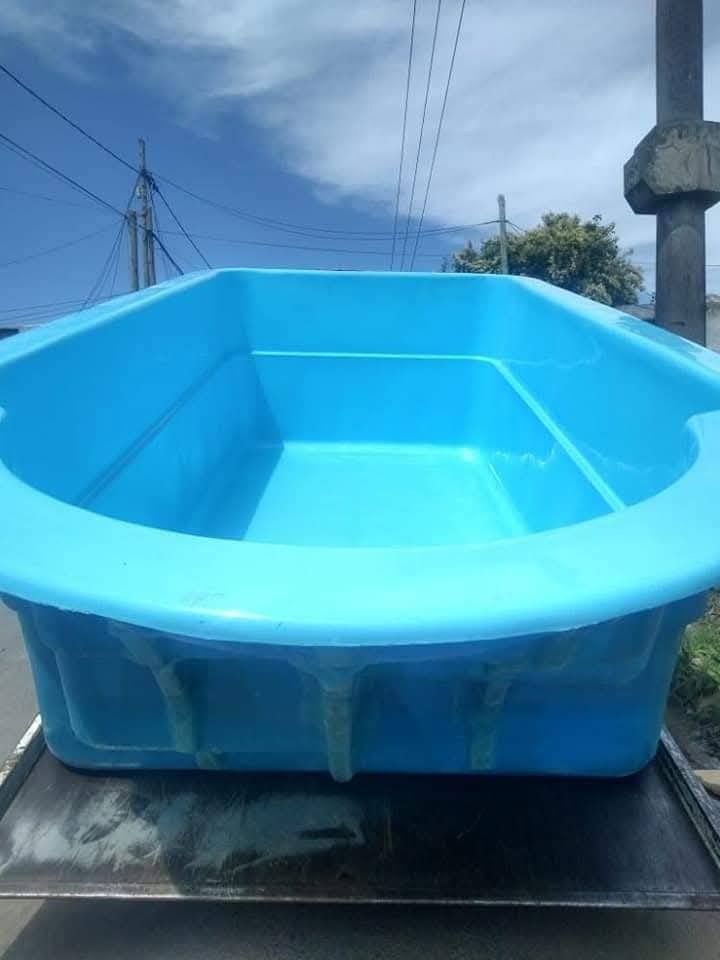 Recipiente rectangular de plástico azul. Exterior, sobre una superficie metálica.