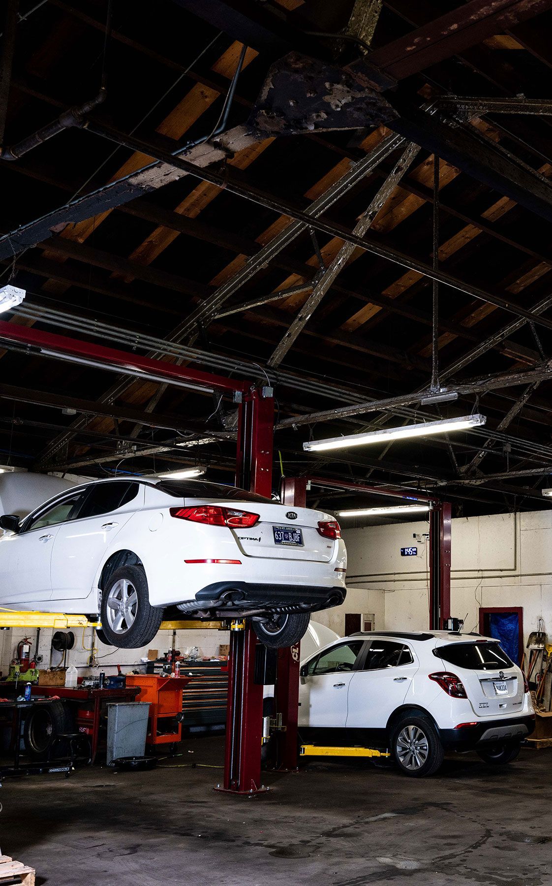 A white kia optima sitting on a lift awaiting repair in the shop at musser automotive in bowling green kentucky