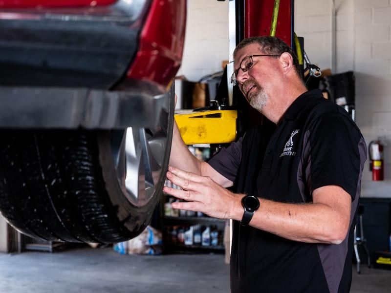 Service manager Dwayne inspecting a vehicle’s tire on a lift at Musser Automotive.