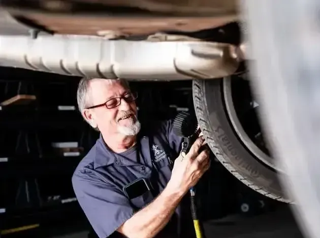 Senior technician Ron airing up a tire on a vehicle lift at Musser Automotive, specializing in auto repair services.