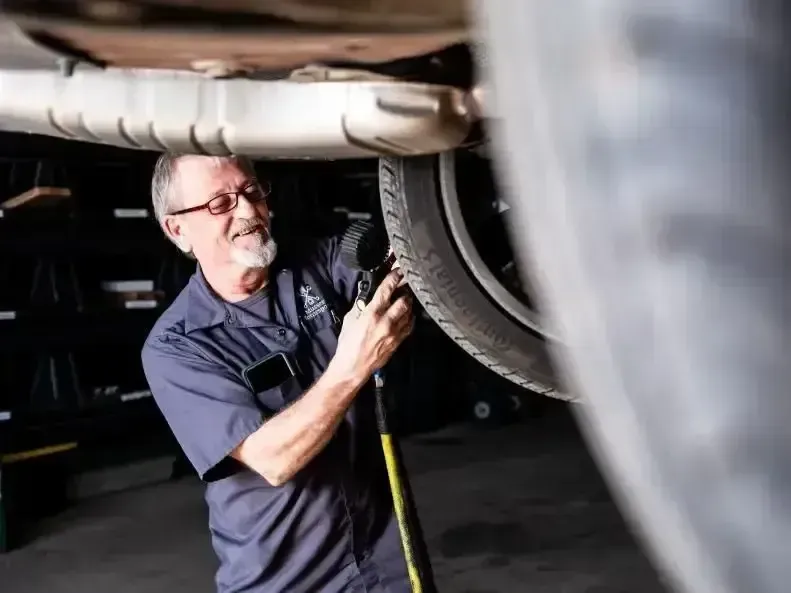 Senior technician Ron airing up a tire on a vehicle lift at Musser Automotive, specializing in auto repair services.