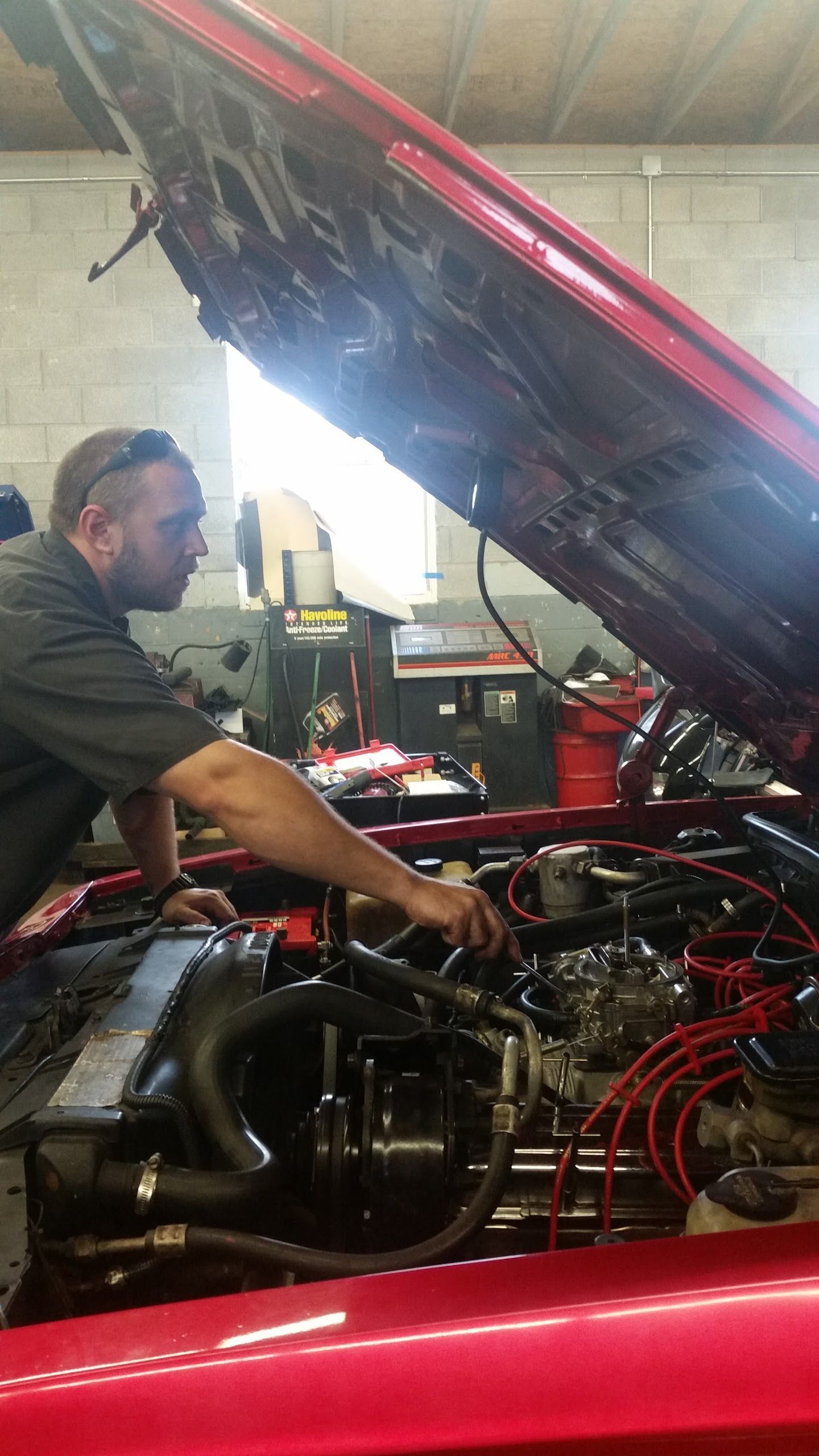 Owner Jason Musser adjusting the carburetor on a classic car at Musser Automotive.