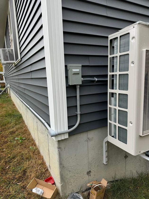 A white air conditioner is mounted on the side of a house.