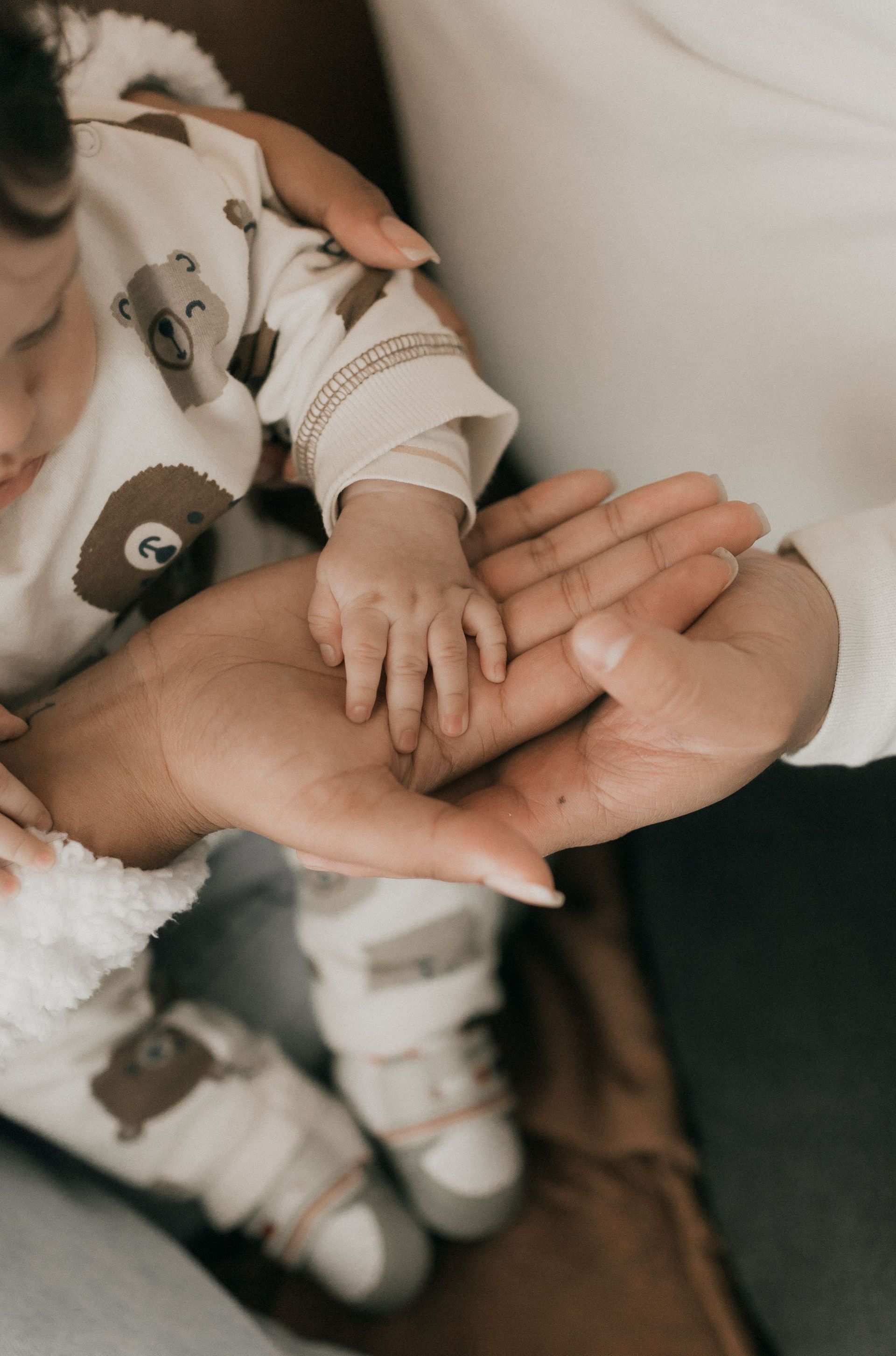 Couple gently holding their newborn baby's hand, representing new parent estate planning in CA