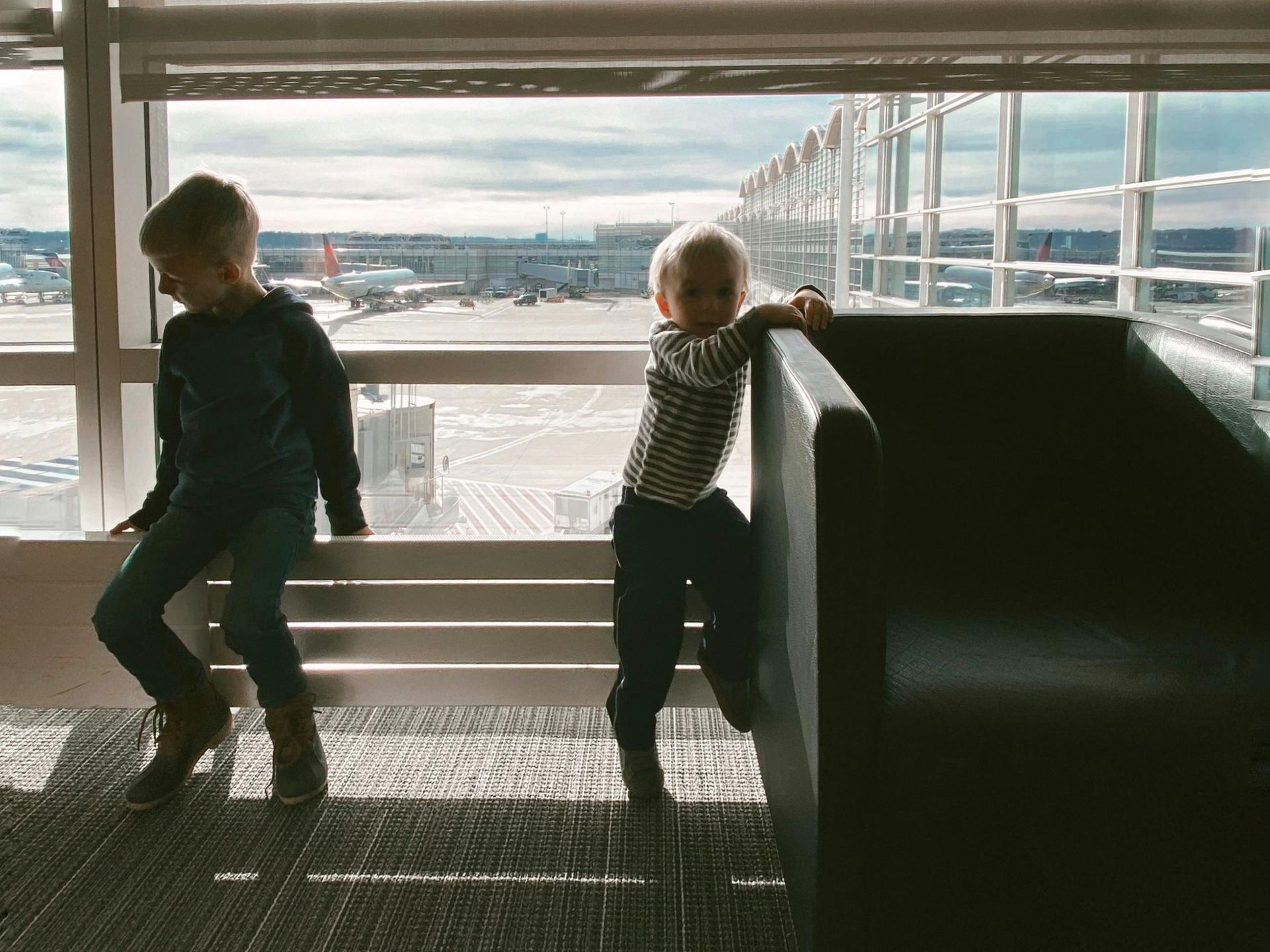 Two smiling children at the airport, ready for vacation, protected by their parents' Kids Protection Plan®.