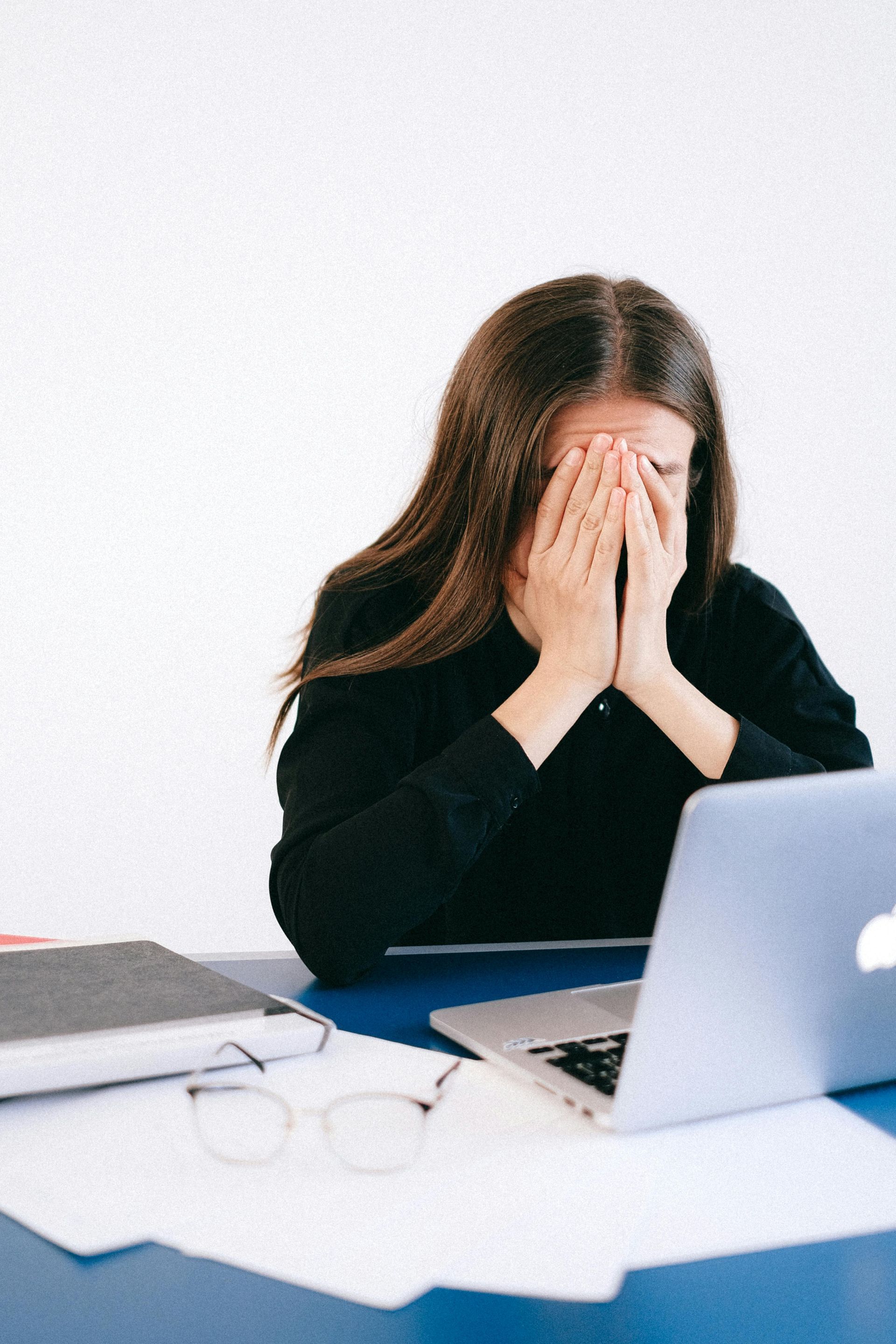 Stressed woman at work with head in hands, representing job stress and family medical leave concerns
