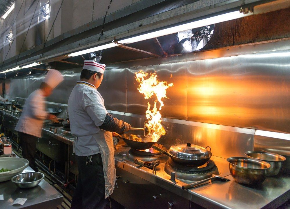 A Chef is Cooking Food on a Stove in a Kitchen ā Kowin Restaurant in Forster, NSW