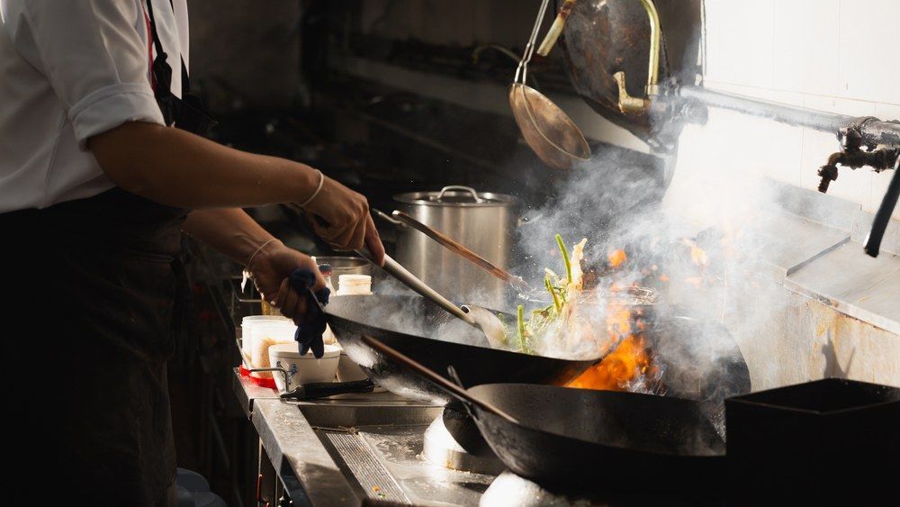 A Chef is Cooking Food in a Wok in a Kitchen — Kowin Restaurant in Old Bar, NSW
