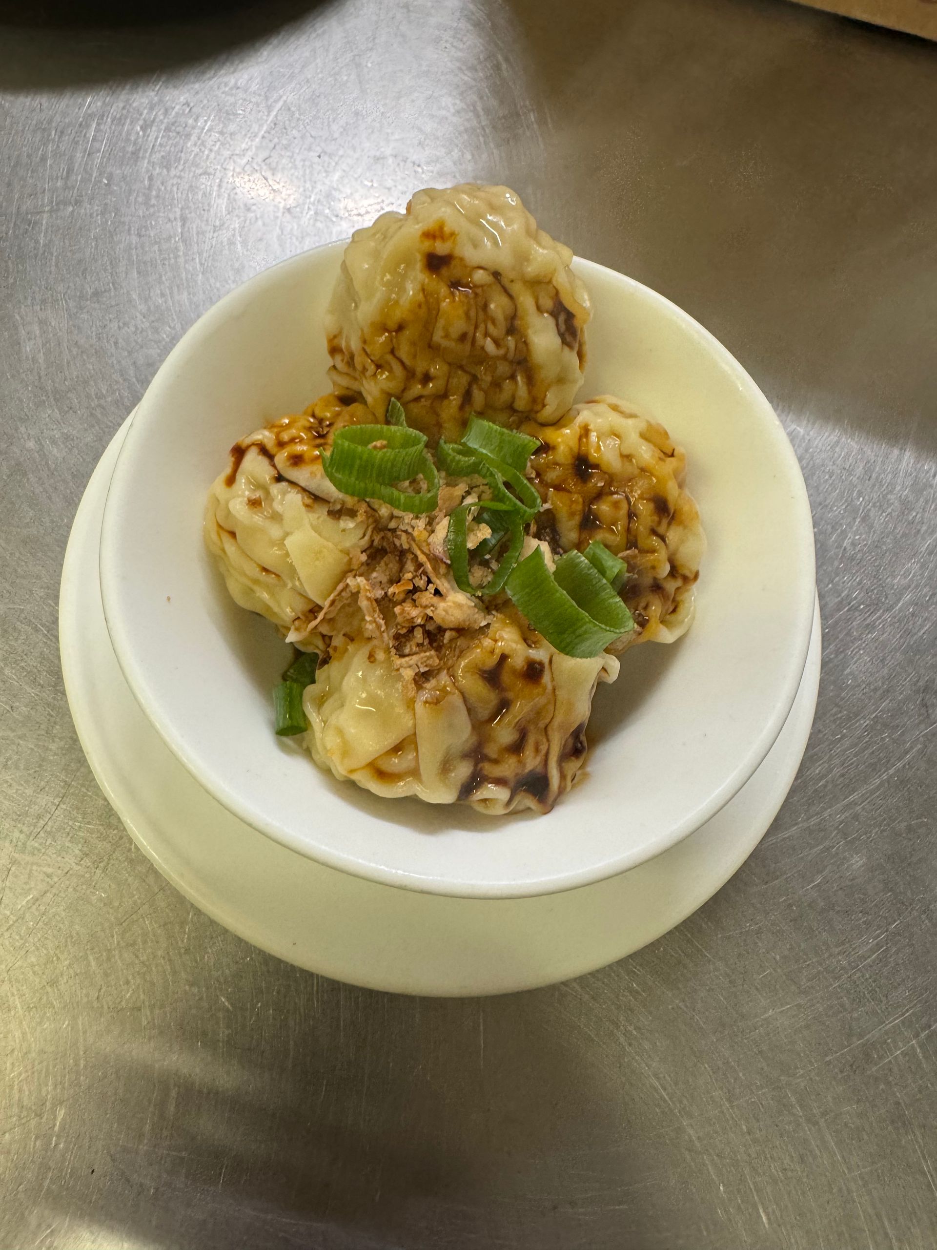 Dumplings in a white bowl, drizzled with sauce, garnished with green onions. — Kowin Restaurant in Taree, NSW