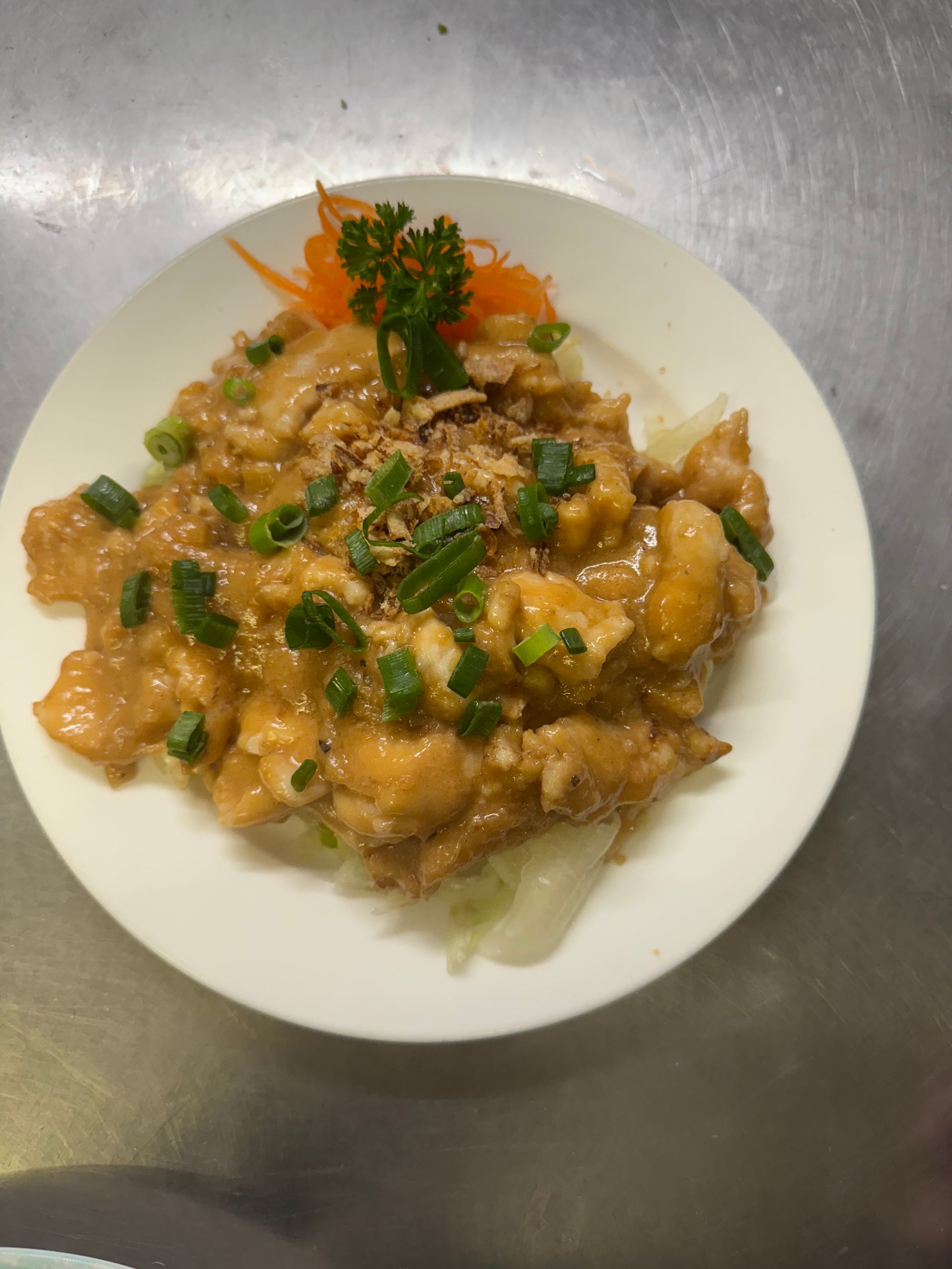 Chicken dish with creamy sauce, scallions, and fried onions on a white plate, garnished with carrots and parsley. — Kowin Restaurant in Old Bar, NSW