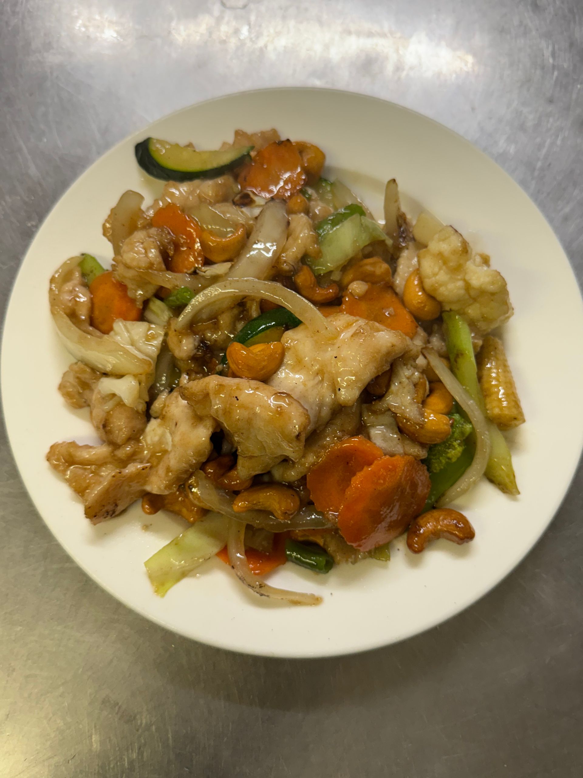 Chicken and vegetable stir-fry with cashews on a white plate. Includes carrots, zucchini, and onions. — Kowin Restaurant in Forster, NSW