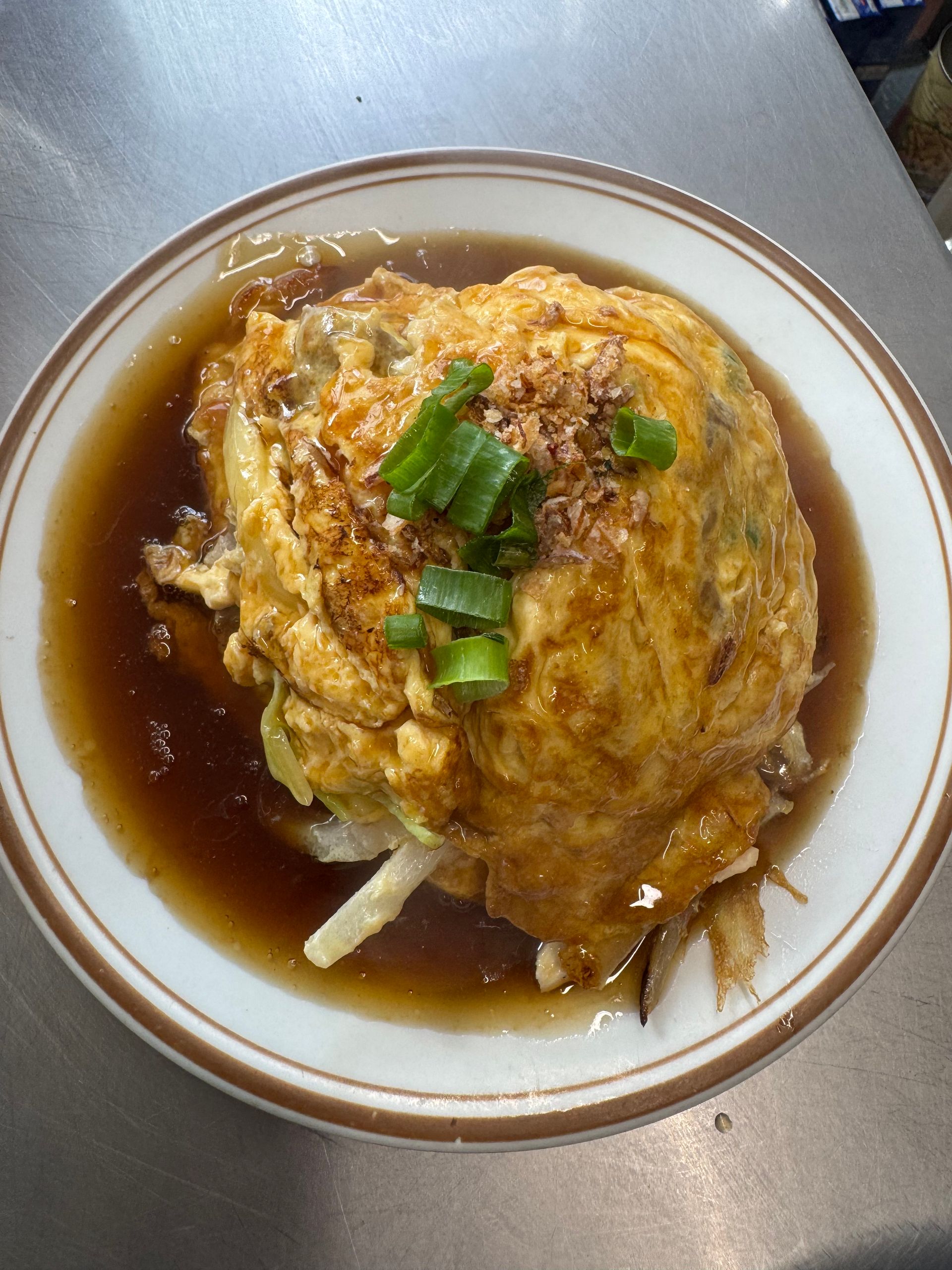 A Plate of Food With a Spoon and Napkin on a Wooden Table — Kowin Restaurant in Harrington, NSW