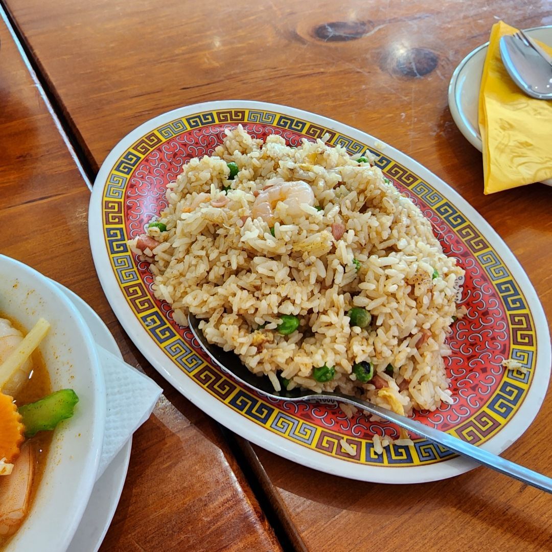A Plate of Fried Rice With a Spoon on a Wooden Table — Kowin Restaurant in Wingham, NSW
