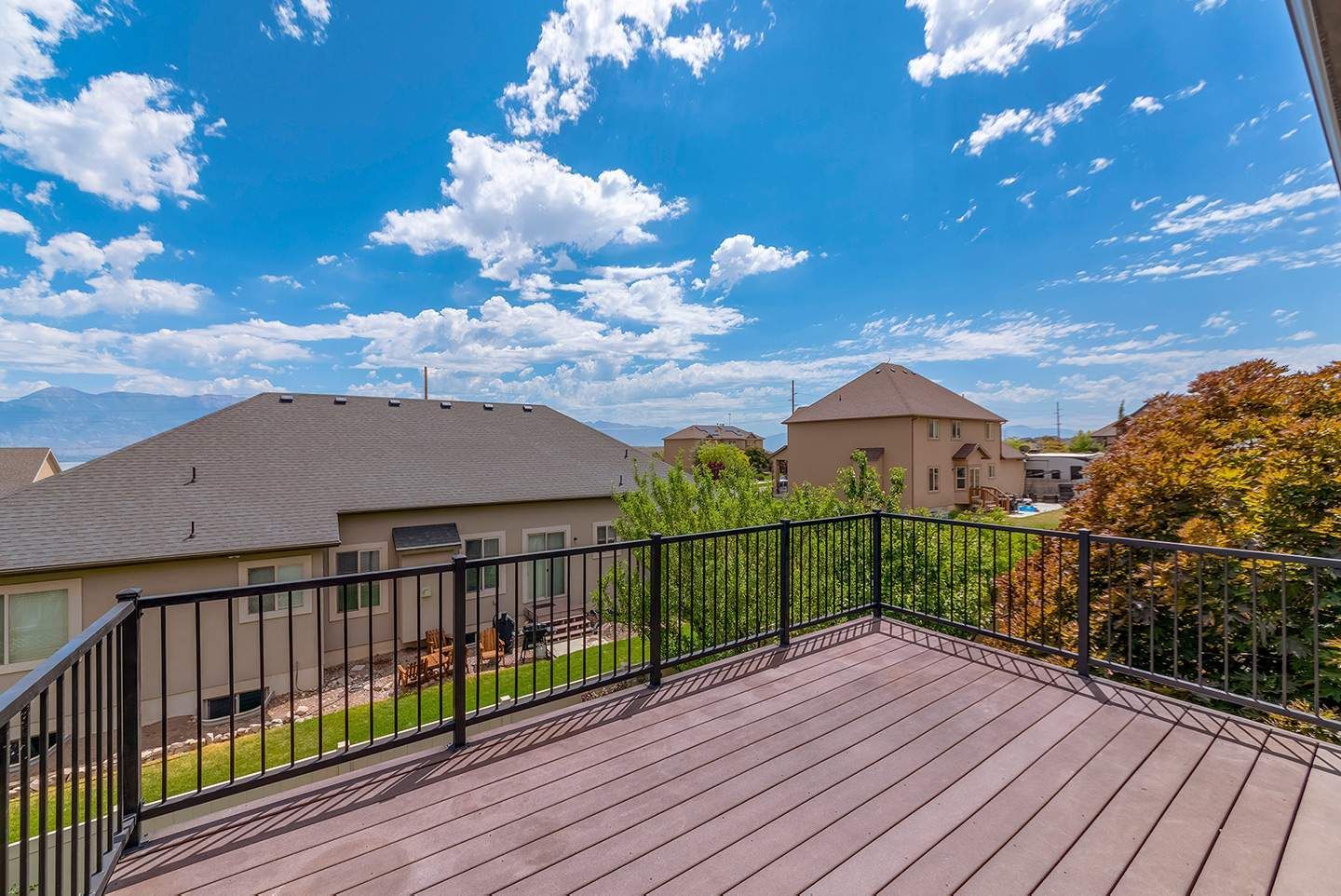 Wooden deck overlooking a suburban neighborhood, blue sky with clouds.
