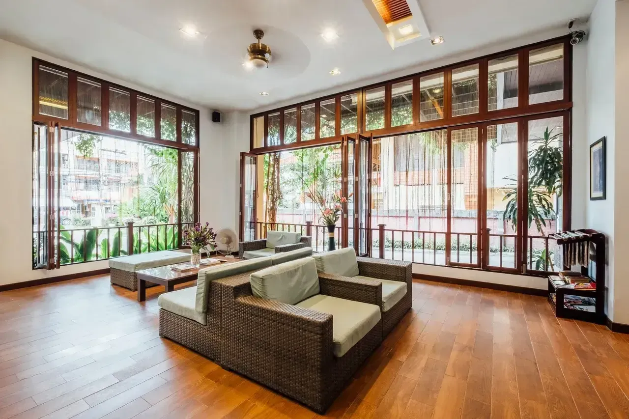 Living room with brown wicker furniture, large windows, and wooden floors.