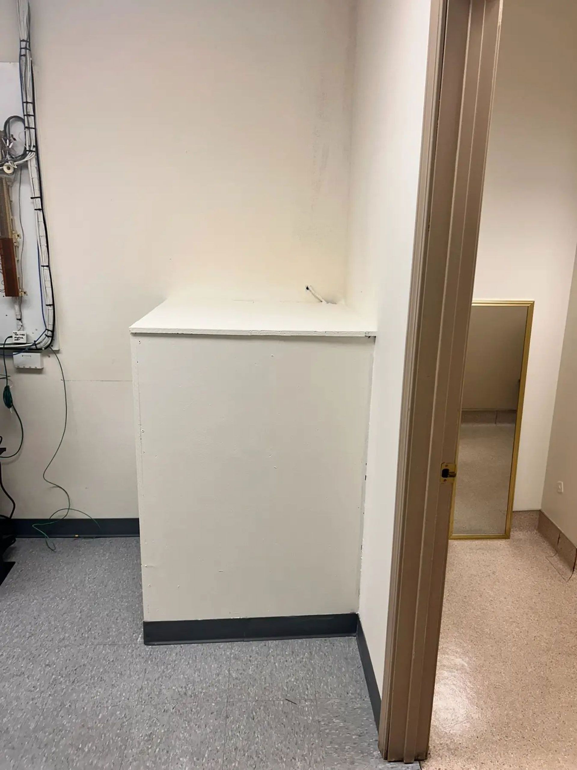 A corner of a room with a white cabinet and a door