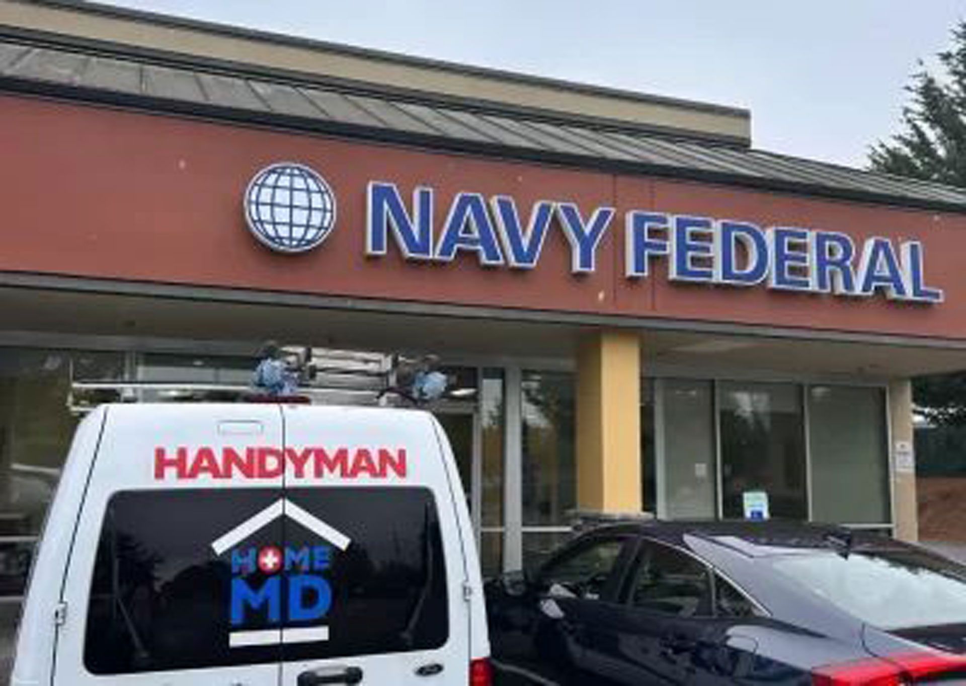 A handyman van is parked in front of a Navy Federal Building