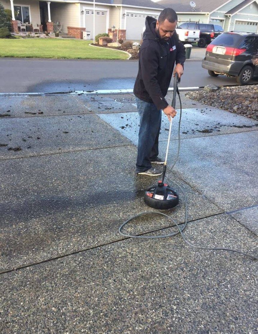 A man is cleaning a driveway with a machine