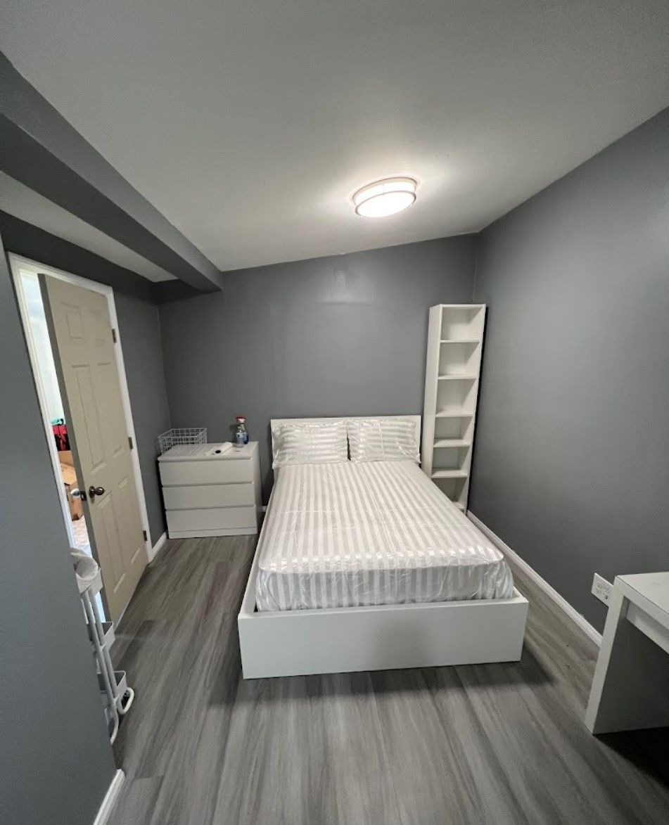 A bedroom with a bed, dresser, nightstand, and shelves