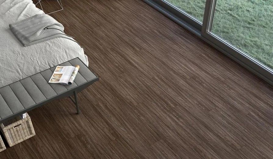 A bedroom with a wooden floor , a bed , a bench and a window.